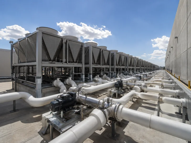 Bank of outdoor data center chillers and pumps sized for redundancy beside a server hall